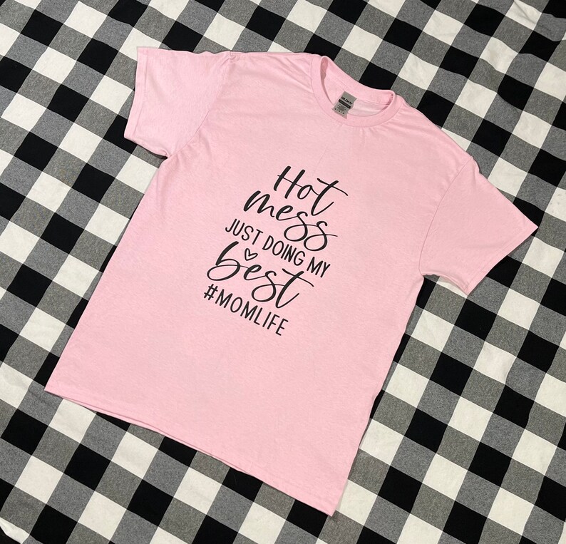 May include: Pink t-shirt with black text that reads "Hot mess just doing my best #momlife"