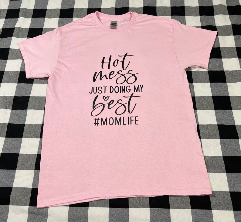 May include: Pink t-shirt with black text that reads "Hot mess just doing my best #momlife".