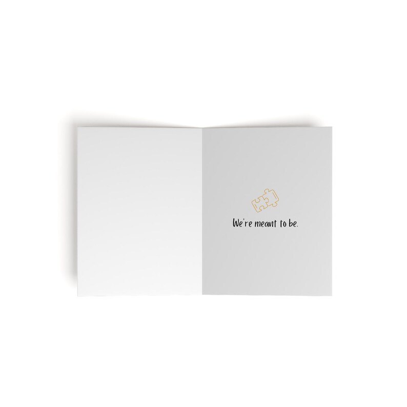 May include: A white card with a gold puzzle piece icon and the text "We're meant to be."