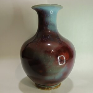 Könnte beinhalten: Eine große, dunkelrote und blaue Keramikvase mit breiter Basis und schmalem Hals. Die Vase hat eine glänzende Oberfläche und einen dezenten irisierenden Schimmer.