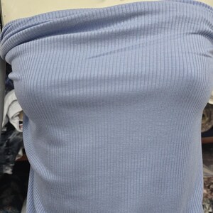 Puede incluir: Un top tipo tubo de color azul claro con textura acanalada y un lazo de tela a juego que se ata alrededor del cuello. La prenda est&aacute; confeccionada en un material suave y texturizado con rayas verticales, ofreciendo un ajuste ce&ntilde;ido al torso.