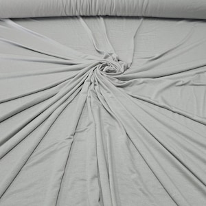 May include: A close-up of a light gray fabric, folded and arranged in a circular pattern. The fabric is soft and smooth, with a subtle sheen.