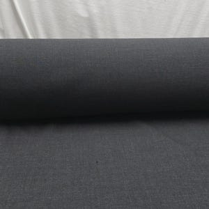 May include: A roll of dark gray fabric, likely textile material, is displayed against a white background. The fabric is tightly rolled, showcasing its texture and color. The image highlights the material's potential for various uses.