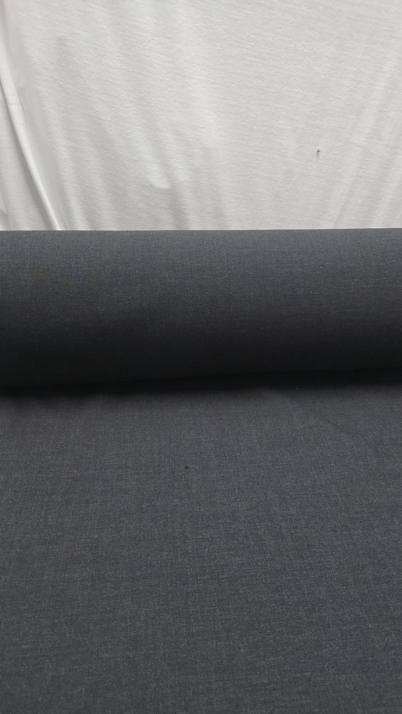 May include: A roll of dark gray fabric, likely textile material, is displayed against a white background. The fabric is tightly rolled, showcasing its texture and color. The image highlights the material's potential for various uses.