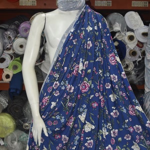 May include: A blue fabric with a white and pink floral print. The fabric is draped over a white mannequin.
