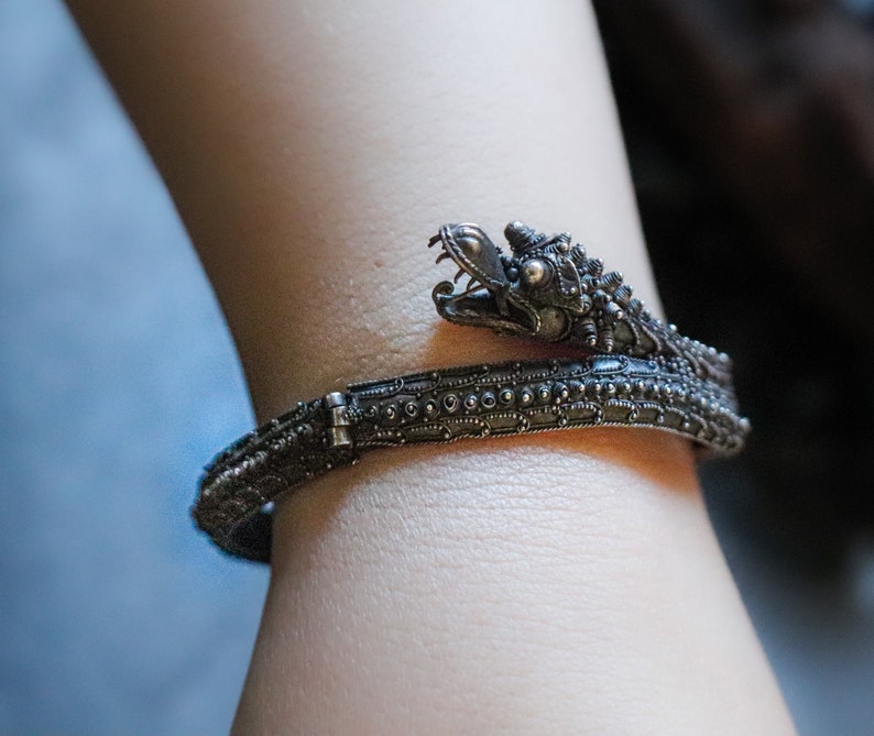 Pu&ograve; includere: Un braccialetto d'argento con un design a testa di drago. Il braccialetto &egrave; dettagliato con piccole perline e ha una chiusura a cerniera.