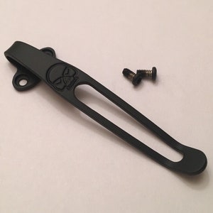 Puede incluir: Clip de bolsillo de titanio negro con un dise&ntilde;o de calavera y dos peque&ntilde;os tornillos negros.