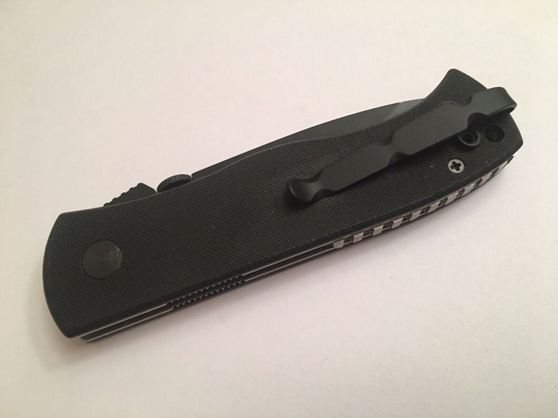 May include: Black folding knife with a black pocket clip and a textured black handle.