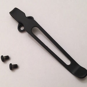 Puede incluir: Clip de bolsillo de metal negro con dos pequeños tornillos negros.