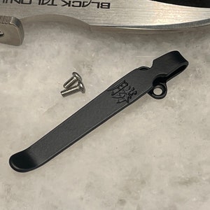 May include: Black pocket clip with a small hole and a logo engraved on it. Two silver screws are included.