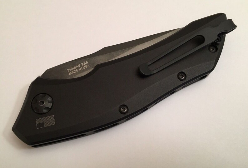 May include: Black folding knife with a pocket clip and the text "71008W  CAI MADE IN USA" engraved on the side.