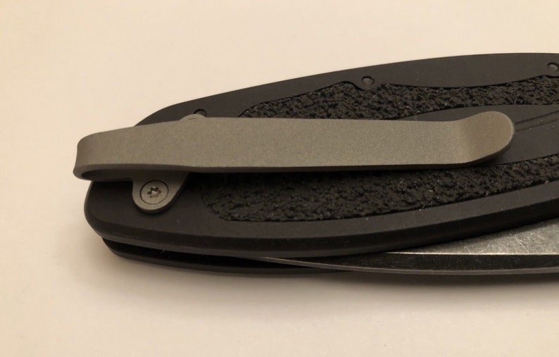 May include: A black pocket knife with a textured handle and a silver pocket clip.