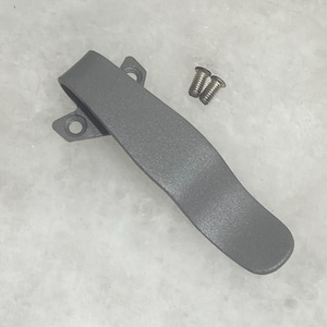 May include: A gray plastic handle with two screw fasteners. The handle has a curved design and two mounting points with holes. The screws are silver and have a slotted head.
