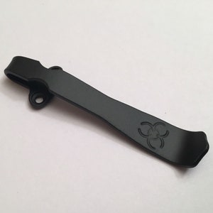 May include: Black metal pocket clip with a biohazard symbol engraved on it.