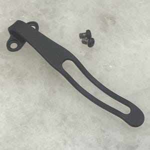 May include: Black metal pocket clip with two small screws. The clip is designed to attach to a pocket or belt.