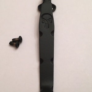 Pu&ograve; includere: Portachiavi in metallo nero con un design a forma di teschio. Il clip &egrave; fissato a un portachiavi con due viti.