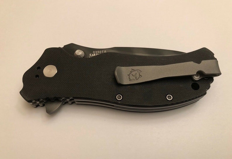 Puede incluir: Un cuchillo plegable negro con mango negro y clip de bolsillo plateado. El cuchillo tiene un mango texturizado y un clip plateado con un logotipo. El cuchillo tiene el n&uacute;mero 0350TS en el lateral.