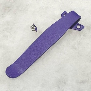 May include: Purple metal pocket clip with two screws. The clip has a textured finish.