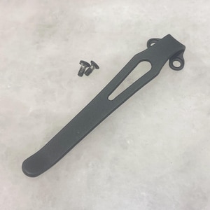 May include: Black metal pocket clip with two small screws. The clip has a curved shape and a small hole in the center.