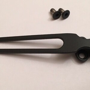 May include: Black metal pocket clip with two screws. The clip is designed to attach to a pocket or belt.