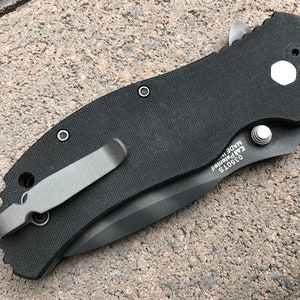 May include: Black pocket knife with a black handle and a silver clip. The knife has a textured handle and a silver blade. The knife is made in the USA and has the model number 03501S.
