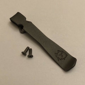 Puede incluir: Un clip de bolsillo de metal negro con un peque&ntilde;o logotipo grabado en la parte inferior. Se incluyen dos tornillos negros.