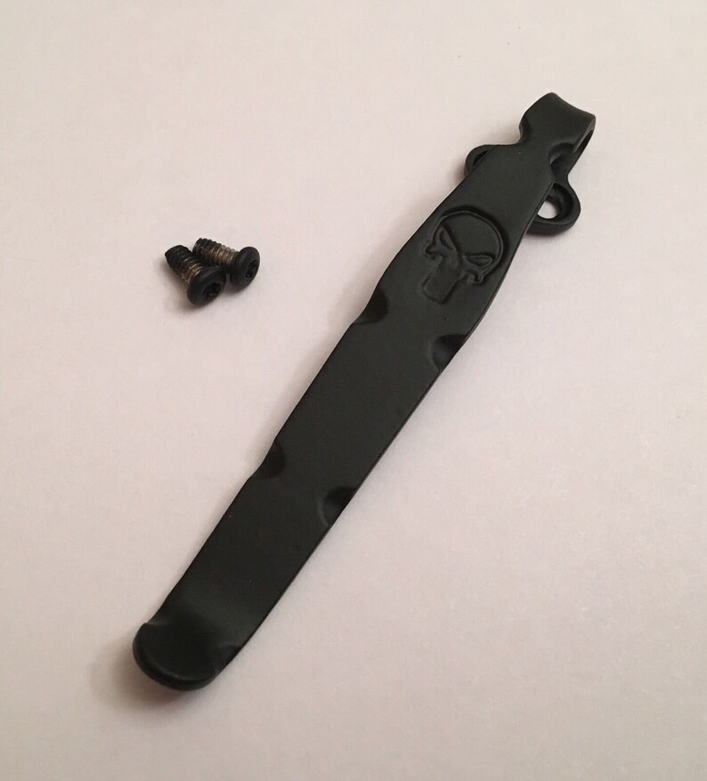 Pu&ograve; includere: Clip da tasca in metallo nero con un design a forma di teschio e due viti.