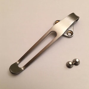 May include: A silver pocket clip with a smooth finish and a rounded end. Two small silver screws are included.