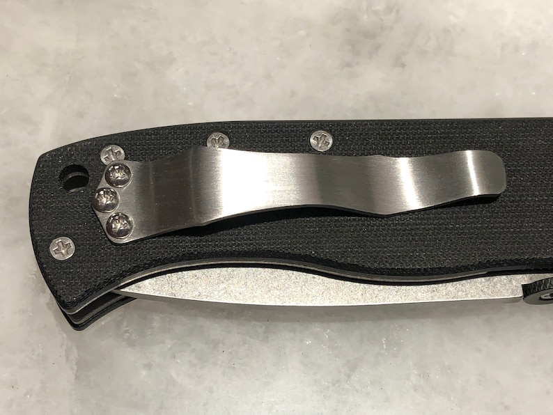 May include: A black pocket knife with a stainless steel clip and a textured black handle.