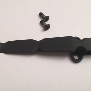 May include: Black metal pocket clip with two screws. The clip has a rounded end and a hole for attaching to a belt or bag.