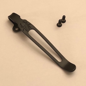 May include: Black metal pocket clip with a spider design. The clip comes with two black screws.