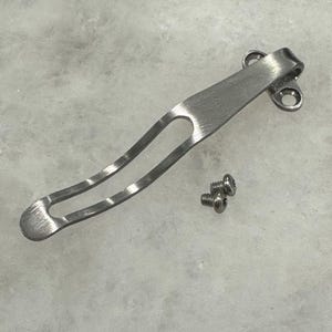 May include: A silver pocket clip with two screws. The clip is designed to attach to a pocket knife or other tool.