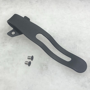 May include: Black metal pocket clip with two small silver screws. The clip is curved and has a single opening.