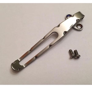 May include: A silver pocket clip with two screws. The clip has a unique design with a curved top and a straight bottom.