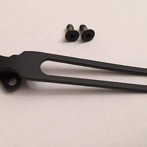 May include: A black metal pocket clip with a rounded end and a small hole on the side. Two small black screws are included.