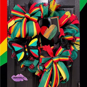 May include: A green, yellow, and red wreath with a black butterfly, a heart, and bows. The wreath is made of mesh and ribbon. The text "CREATIVELY HERS" is visible in the bottom left corner.