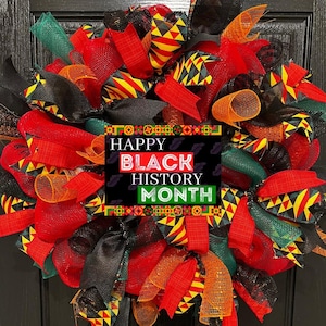 May include: A red, green, black, and yellow wreath with a sign that reads "Happy Black History Month".