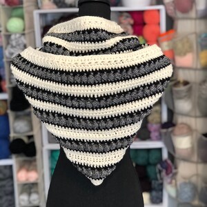 May include: A black and white striped crocheted infinity scarf with a textured design. The scarf is displayed on a black mannequin.