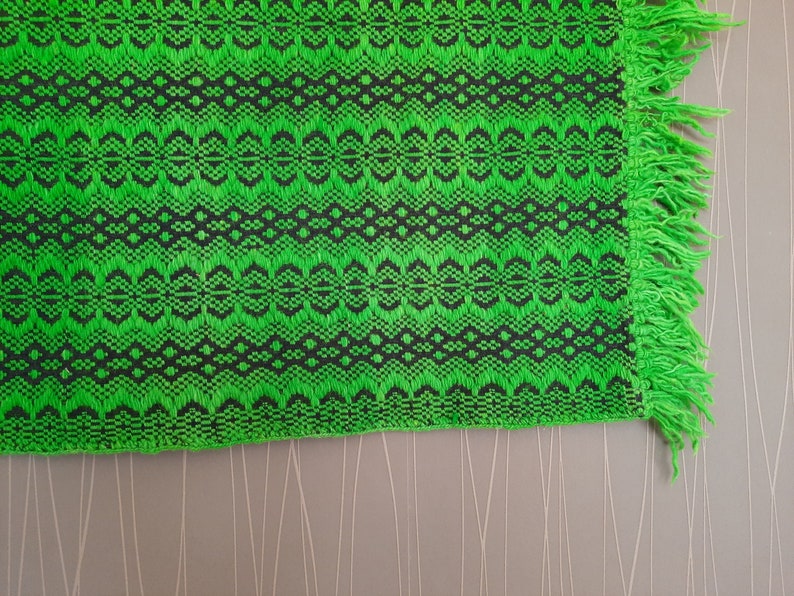 May include: Green and black woven throw blanket with fringe on the edges.