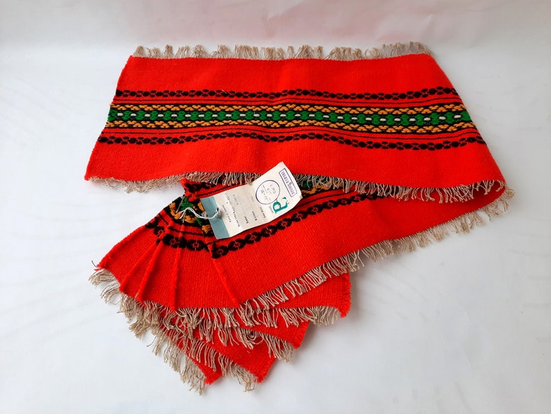 Pu&ograve; includere: Set di sei tovagliette all'americana in tessuto rosso con un motivo geometrico nero, verde e giallo. Le tovagliette hanno bordi a frangia e sono dotate di un'etichetta con la scritta "R" e "Made in Holland".