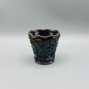 May include: A small, iridescent glass vase with a scalloped rim and intricate, geometric patterns. The vase is a deep purple color with hints of blue and green.