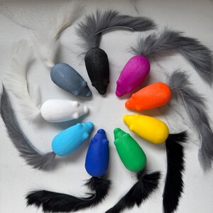 Può includere: Una collezione di topi giocattolo colorati con code soffici. I topi sono in vari colori, tra cui bianco, blu, nero, rosa, arancione, giallo e verde. Le code sono fatte di morbida pelliccia grigia e nera.