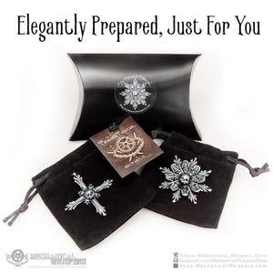 Puede incluir: Dos bolsitas de terciopelo negro con dise&ntilde;os de calavera y copo de nieve de metal plateado. Las bolsitas est&aacute;n empaquetadas en una caja de almohada negra con el texto "Catacomb Collection" y "Mechanical Whispers".