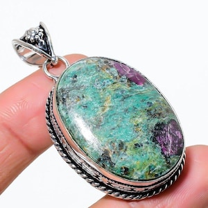 May include: A silver pendant featuring a green and purple gemstone. The gemstone is oval shaped and has a swirling pattern. The pendant has an intricate silver bail.