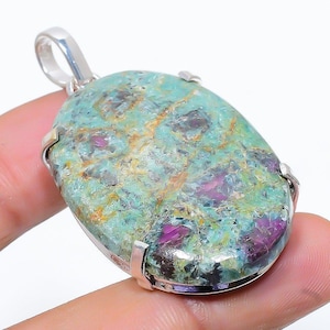 May include: A silver pendant featuring a green and pink oval gemstone with a swirling pattern. The gemstone is set in a silver bezel and has a polished finish.