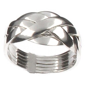 May include: A silver-coloured puzzle ring featuring four interlocking bands that cross over each other at the top to create a woven, lattice-like pattern. The lower portion of the ring consists of four parallel, smooth, solid metal bands.