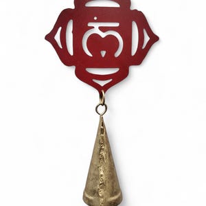 Pu&ograve; includere: Un carillon in metallo rosso con un design a taglio del simbolo sanscrito "Om" e una campana dorata in fondo.