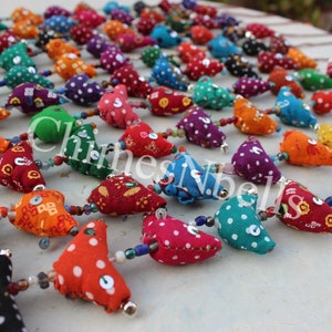 May include: A colorful garland featuring fabric teardrop-shaped ornaments in various colors, including red, orange, green, and purple, adorned with white polka dots. Each ornament is connected by a string of beads and small bells. The text "Chinesevibel" is visible.