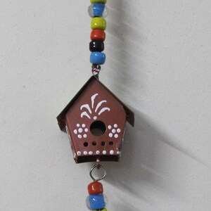 Puede incluir: Una casita de p&aacute;jaros roja y blanca con una campana colgando de ella. La casita de p&aacute;jaros tiene lunares blancos y un dise&ntilde;o blanco en la parte delantera. La campana tambi&eacute;n es roja y blanca con lunares blancos.