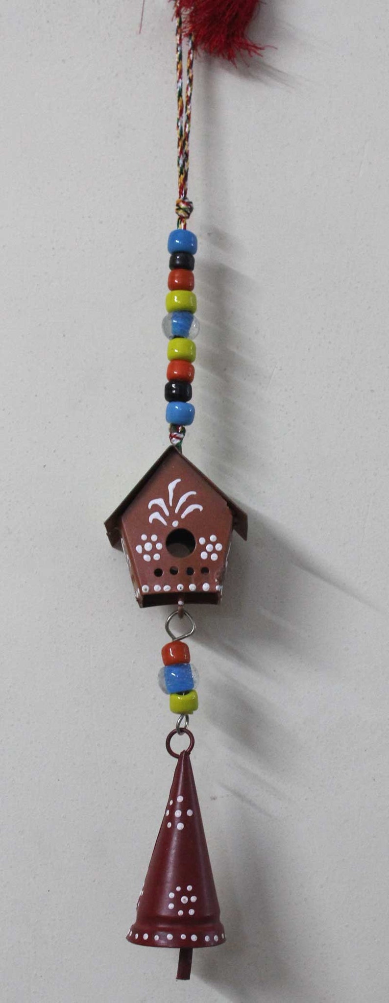 Puede incluir: Una casita de p&aacute;jaros roja y blanca con una campana colgando de ella. La casita de p&aacute;jaros tiene lunares blancos y un dise&ntilde;o blanco en la parte delantera. La campana tambi&eacute;n es roja y blanca con lunares blancos.
